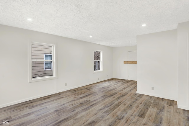 unfurnished room featuring hardwood / wood-style flooring and a textured ceiling