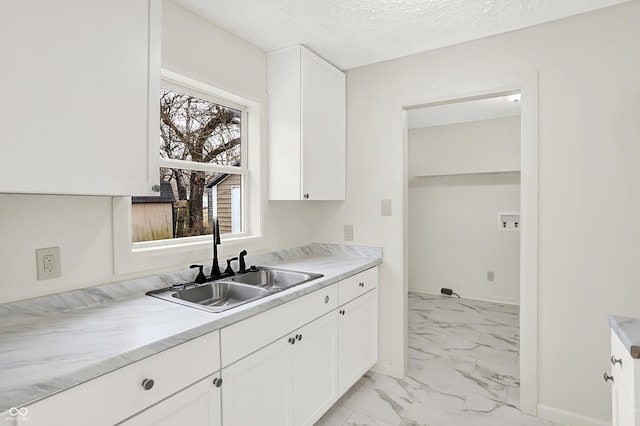 kitchen with white cabinetry, sink, and a textured ceiling