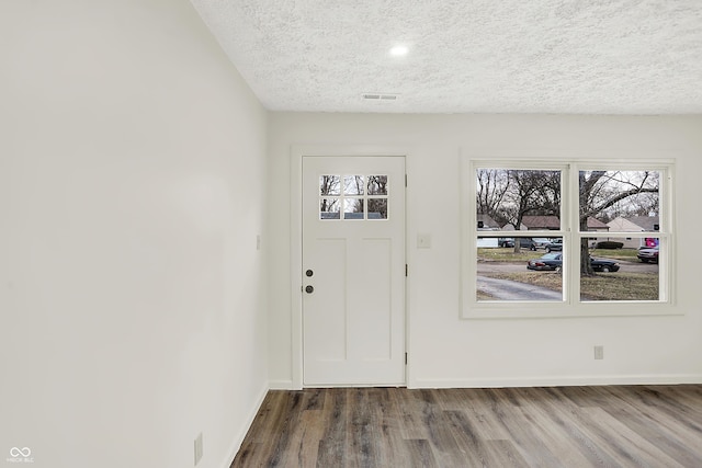 entryway with wood-type flooring and a textured ceiling