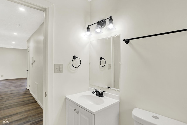 bathroom with hardwood / wood-style flooring, vanity, and toilet