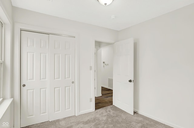 unfurnished bedroom with light carpet and a closet