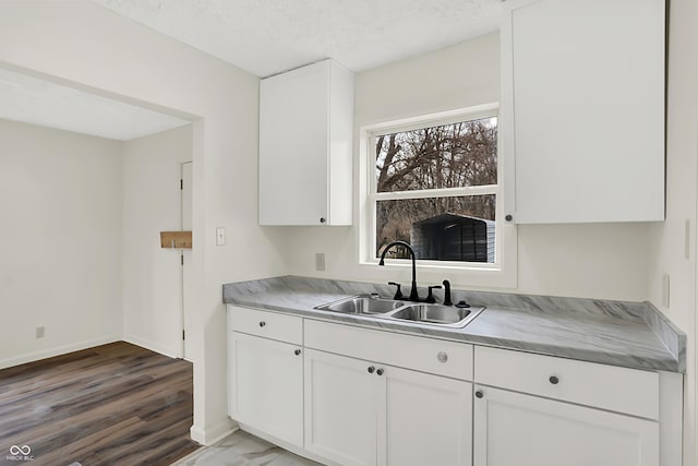 kitchen featuring hardwood / wood-style flooring, sink, white cabinets, and a textured ceiling