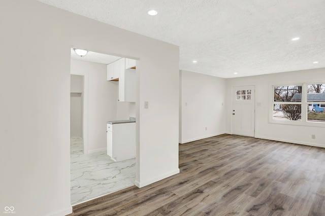 unfurnished living room with hardwood / wood-style flooring and a textured ceiling