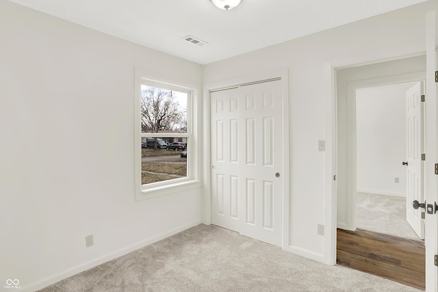 unfurnished bedroom with light colored carpet and a closet