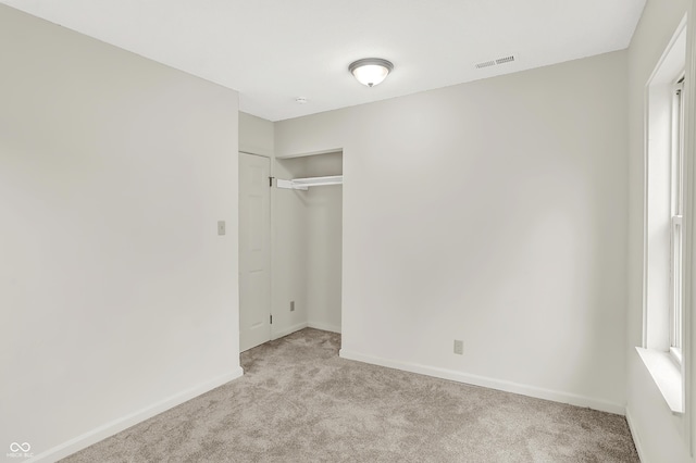 unfurnished bedroom with multiple windows, light colored carpet, and a closet