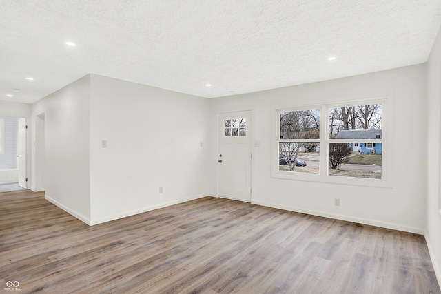 empty room with light hardwood / wood-style flooring and a textured ceiling