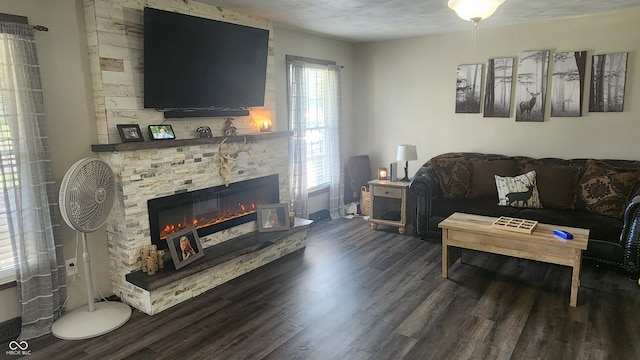 living room featuring dark wood-type flooring, a textured ceiling, and a stone fireplace