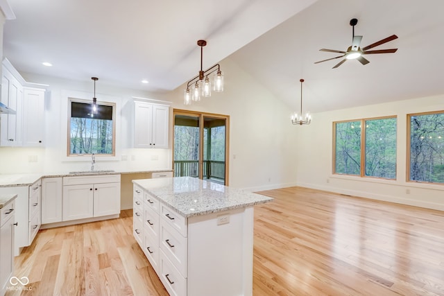 kitchen with vaulted ceiling, ceiling fan with notable chandelier, white cabinets, and light hardwood / wood-style floors