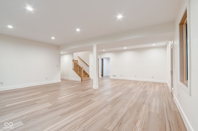 finished basement featuring stairway, baseboards, recessed lighting, and light wood-style flooring