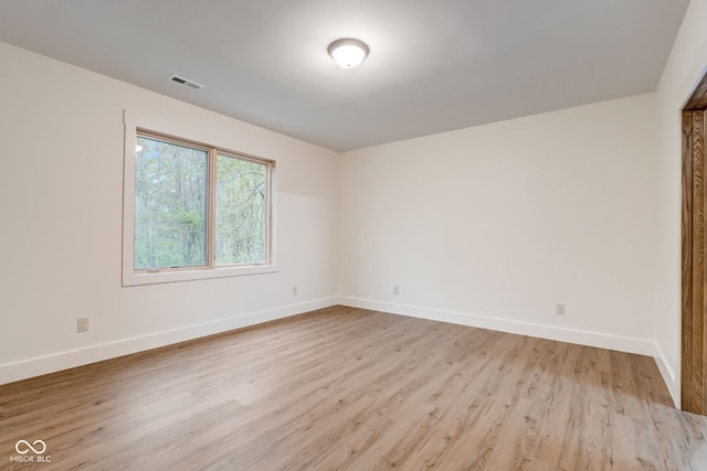 unfurnished room with visible vents, light wood finished floors, and baseboards