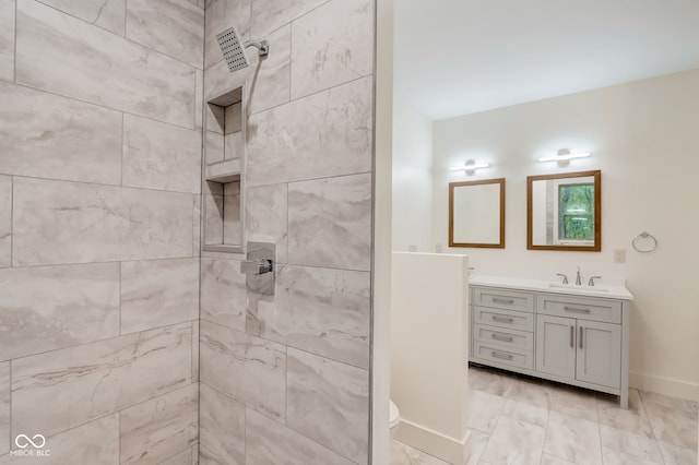 full bath featuring a tile shower, baseboards, toilet, and vanity