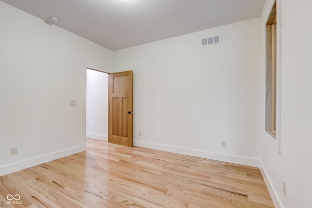 spare room featuring baseboards, wood finished floors, and visible vents