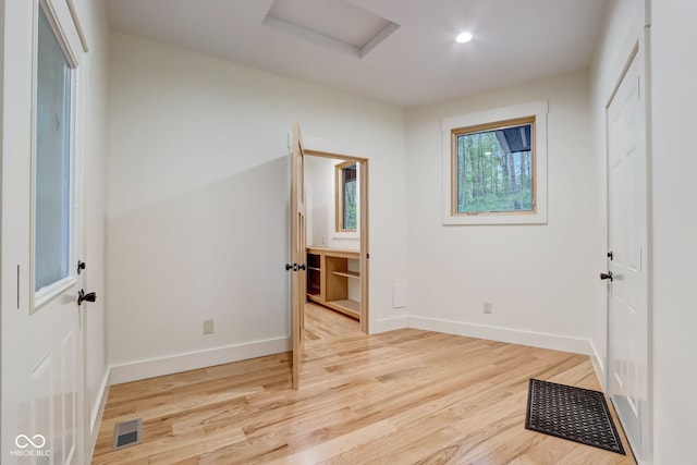 unfurnished bedroom featuring attic access, baseboards, light wood-style floors, and visible vents