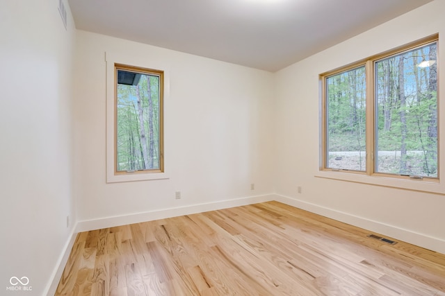 spare room featuring baseboards, light wood finished floors, and visible vents