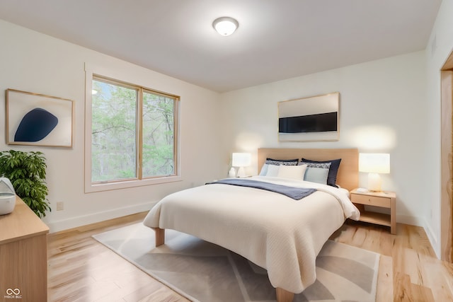 bedroom featuring light wood finished floors and baseboards