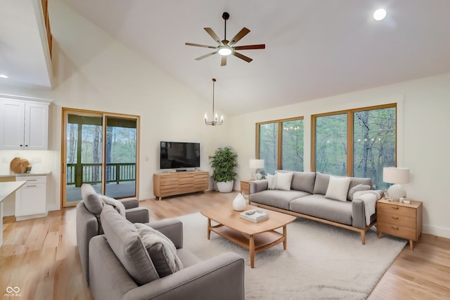 living room featuring a wealth of natural light, ceiling fan with notable chandelier, high vaulted ceiling, and light hardwood / wood-style floors