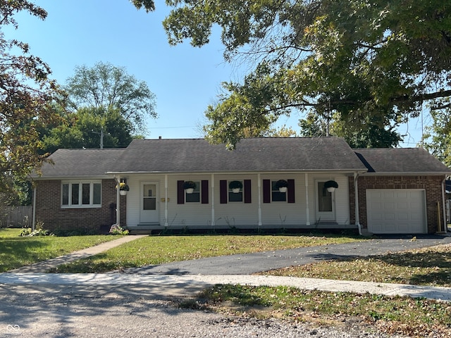 ranch-style house featuring a garage, covered porch, and a front lawn