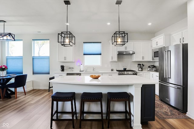 kitchen with high end appliances, a center island, wood-type flooring, and white cabinets