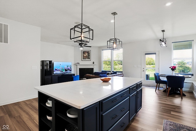 kitchen with decorative light fixtures, a center island, and dark hardwood / wood-style flooring