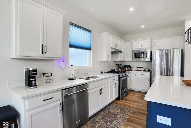 kitchen with light stone counters, stainless steel appliances, white cabinets, dark wood-type flooring, and sink