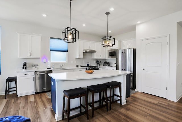 kitchen with pendant lighting, white cabinetry, stainless steel appliances, a center island, and dark hardwood / wood-style flooring