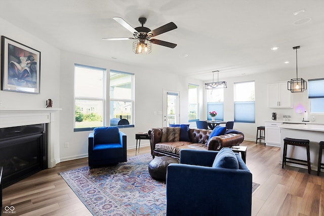 living room featuring plenty of natural light, ceiling fan with notable chandelier, and wood-type flooring