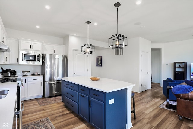 kitchen with blue cabinets, white cabinets, appliances with stainless steel finishes, and light wood-type flooring