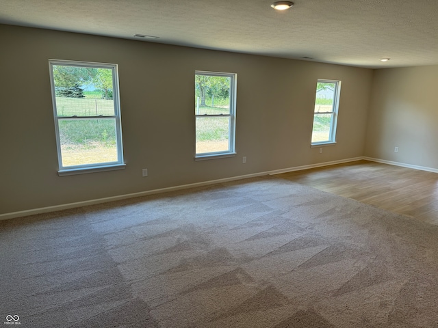 empty room featuring a textured ceiling and light hardwood / wood-style flooring