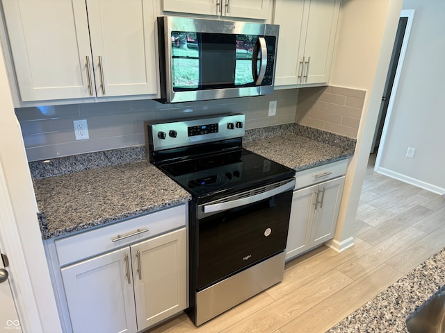 kitchen with appliances with stainless steel finishes, white cabinetry, light hardwood / wood-style flooring, and tasteful backsplash