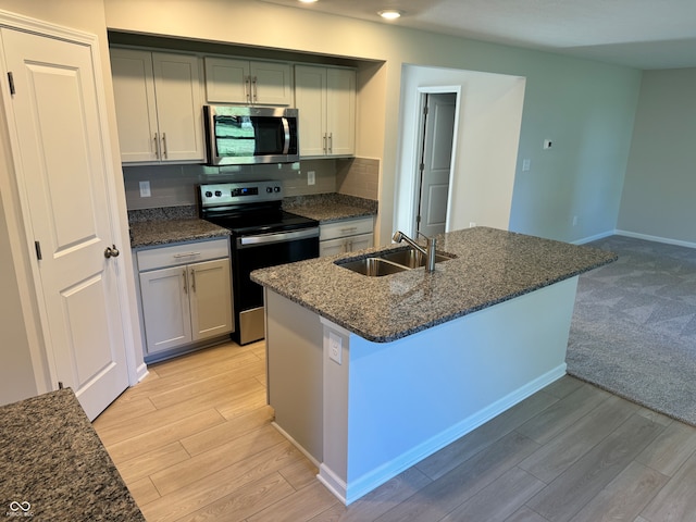 kitchen with stainless steel appliances, light wood-type flooring, sink, and tasteful backsplash