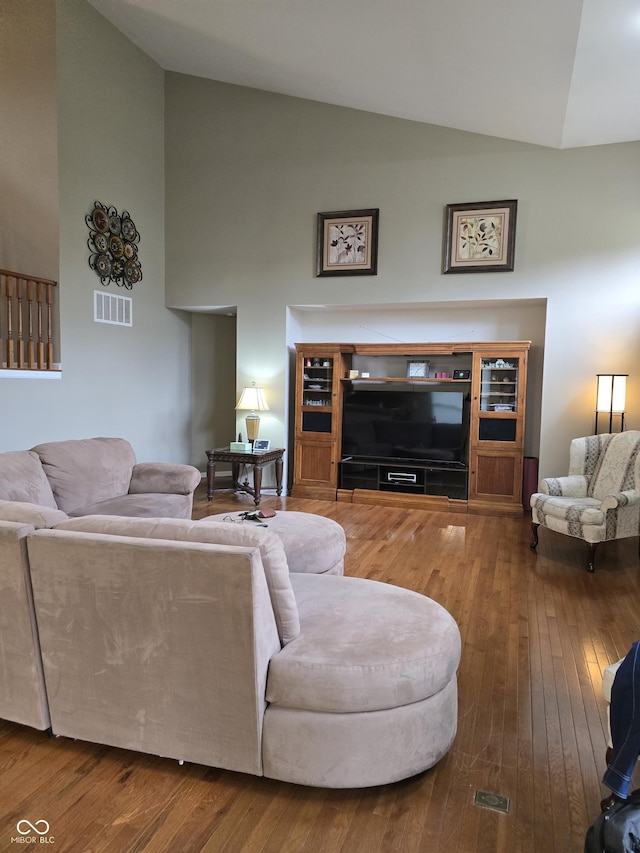 living room featuring visible vents, high vaulted ceiling, and hardwood / wood-style flooring