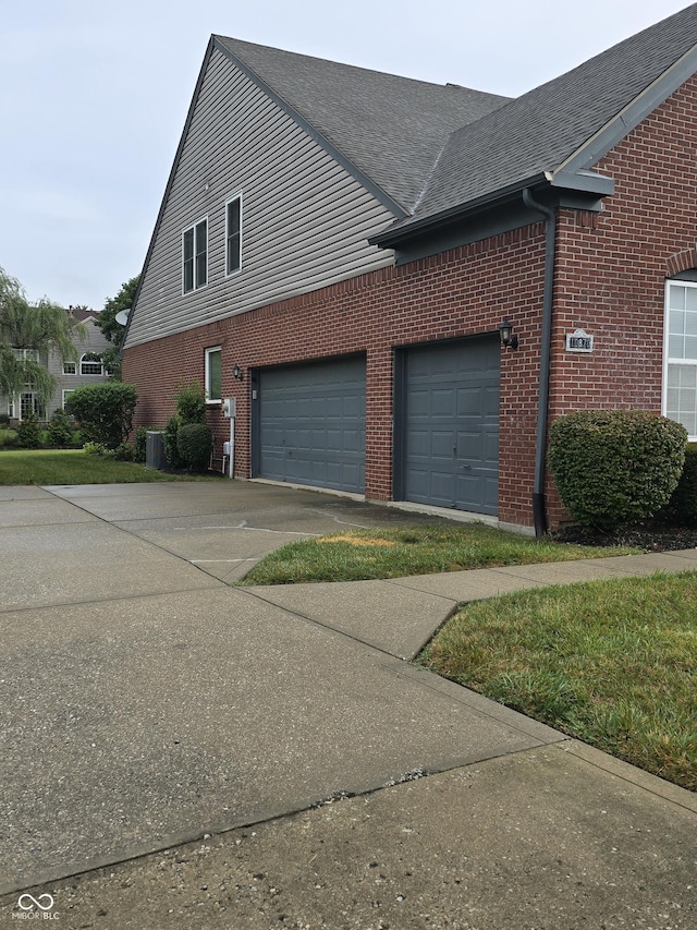 view of home's exterior featuring central air condition unit, brick siding, roof with shingles, and driveway