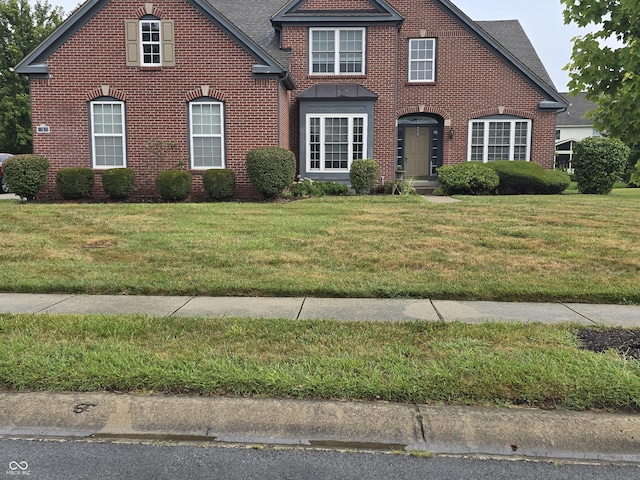 view of front of house with brick siding, roof with shingles, and a front yard