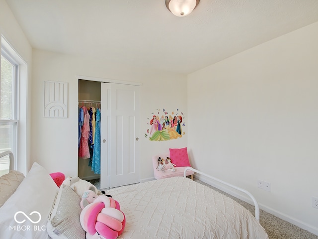 carpeted bedroom with a closet and baseboards