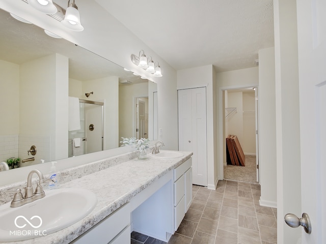 full bath featuring a sink, a shower stall, baseboards, and double vanity