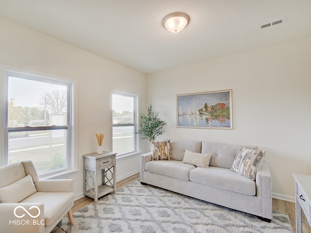 living area featuring light wood-style floors, baseboards, and visible vents