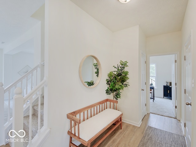 hallway with stairway, light wood-type flooring, and baseboards