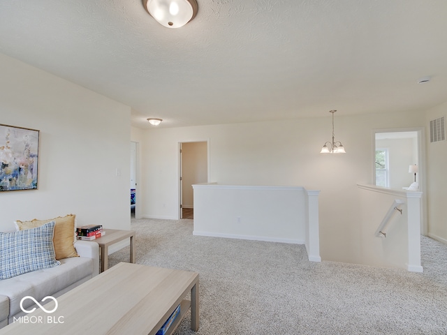 carpeted living area with baseboards, visible vents, a chandelier, and a textured ceiling