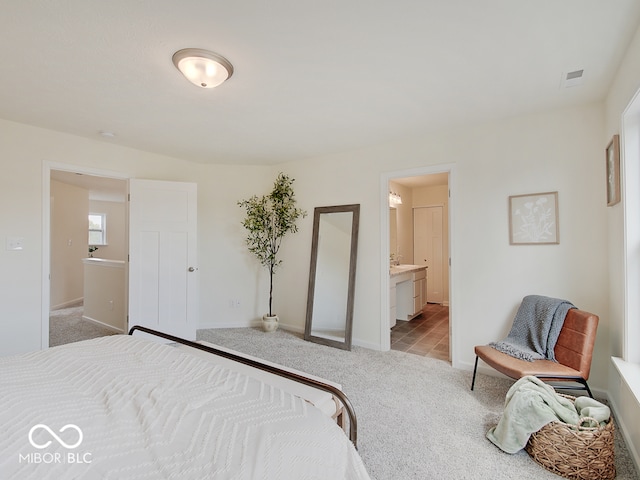 bedroom featuring light carpet, ensuite bath, and baseboards