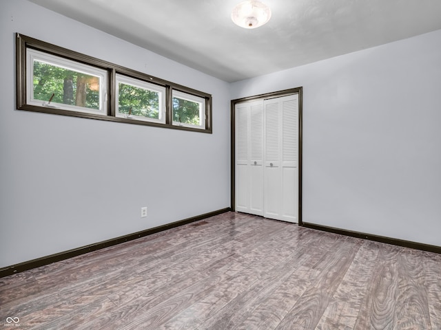 unfurnished bedroom featuring baseboards, a closet, and wood finished floors