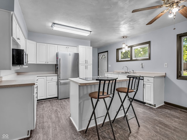 kitchen with stainless steel fridge, a center island, white cabinets, and a breakfast bar