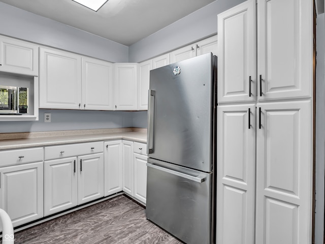 kitchen featuring stainless steel fridge, white cabinetry, and wood-type flooring