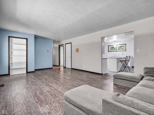 living room with built in shelves, hardwood / wood-style floors, and sink