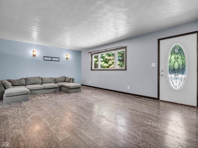 unfurnished living room with hardwood / wood-style flooring and baseboards