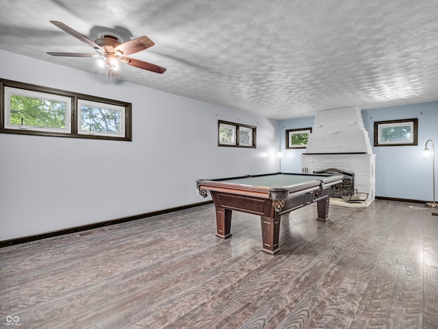 rec room with a textured ceiling, pool table, dark hardwood / wood-style floors, a fireplace, and ceiling fan