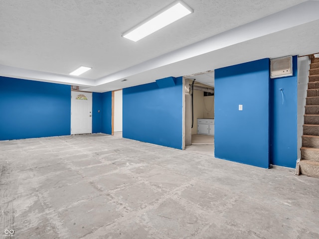 finished below grade area with stairs and a textured ceiling