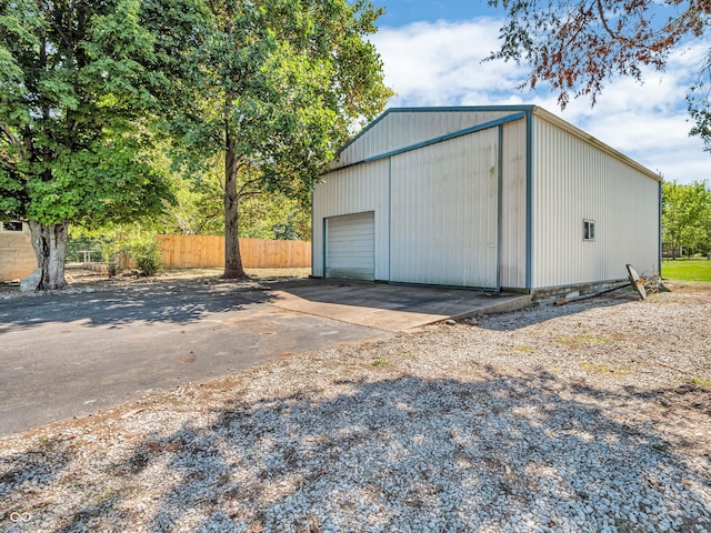 detached garage featuring driveway and fence