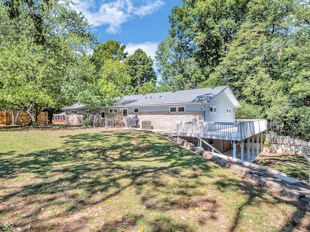 back of property with a wooden deck, fence, and a yard