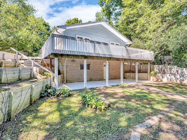 rear view of house featuring a deck, stone siding, a patio area, and fence