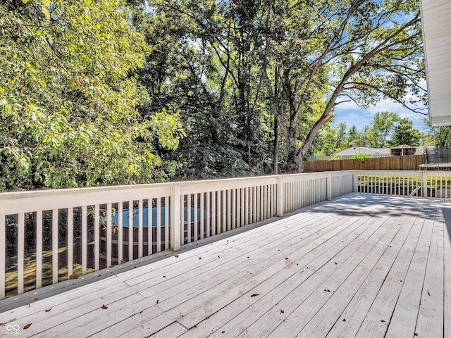 deck featuring a trampoline, fence, and a pool